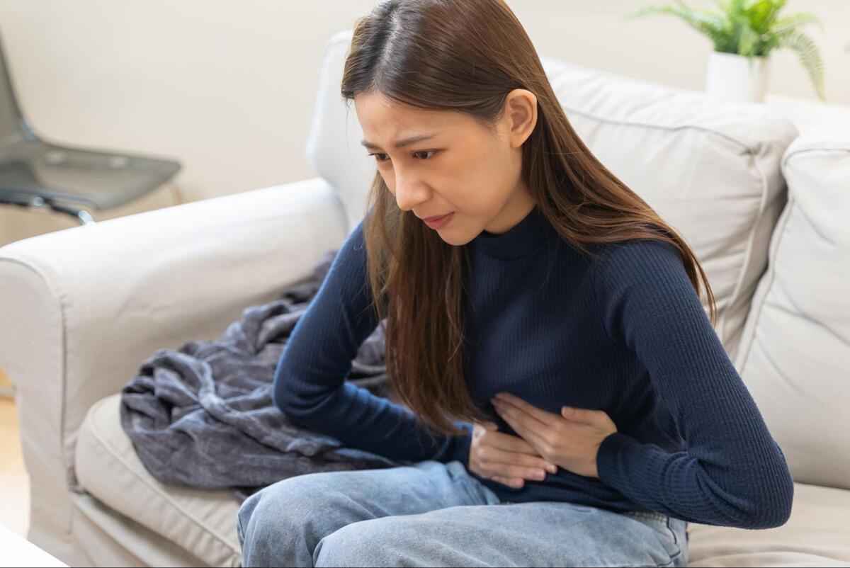 腹部を押さえて痛そうにする女性