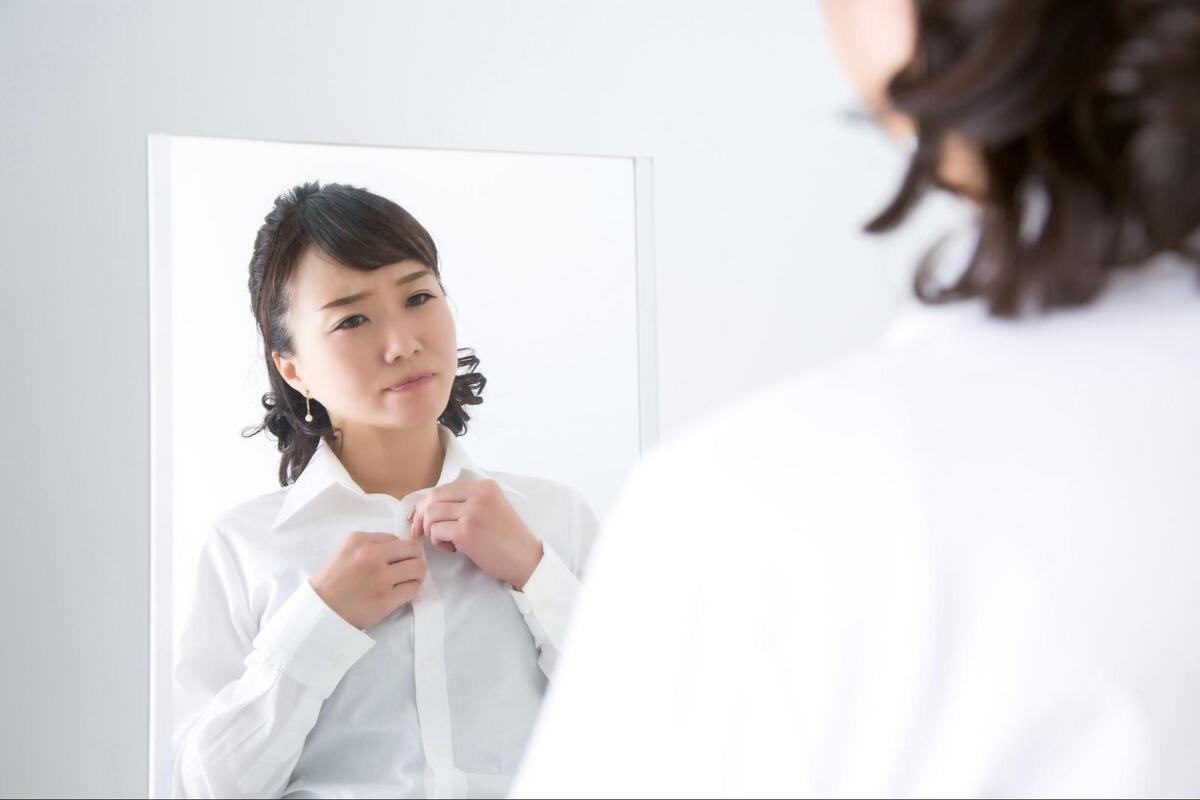 鏡を見ながらボタンを止める女性