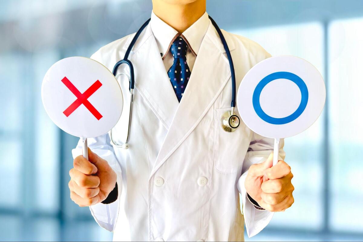 医師が◯と×が書かれたプレートを持っている